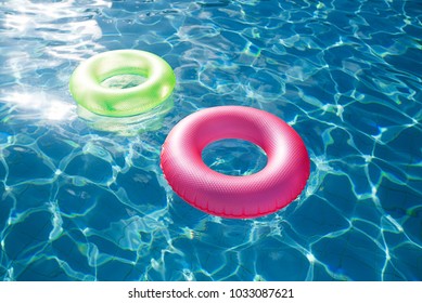 floating rings on blue water swimming pool with waves reflecting in the summer sun