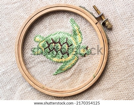 floating sea turtle in wooden hoop embroidered by hand on fabric close up