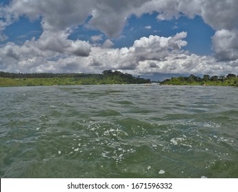 Floating Towards Rapids On The Turbulent Water Of The White Nile River In Jinja, Uganda, With Clouds Overhead And Green Hills To Either Side (shot With GoPro)