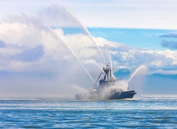 The Floating Tug Boat Is Spraying Jets Of Water, Demonstrating Firefighting Water Cannons