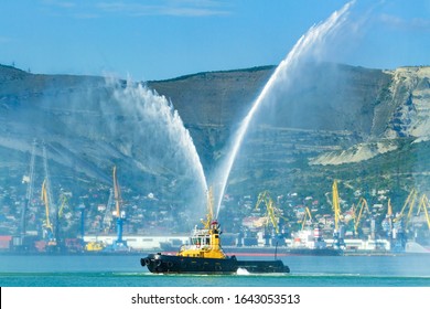 Floating tug boat is spraying jets of water, demonstrating firefighting water cannons