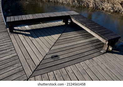 floating walkway made of wooden planks, pier, narrow curved paths on stilts driven to the bottom above the lake water. has no railings. more design sidewalk with low railings for wheelchairs