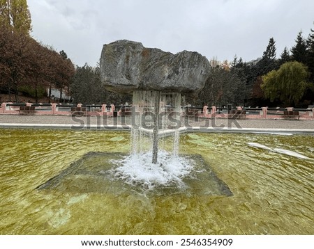 Floating water rock in the pool. Balance rock fountain. Park fountain rock float trick fountains. View to fountain with boulder. Natural rock water fountain.