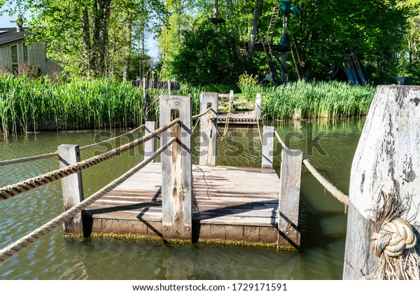 Floating wooden bridge pontoon raft with cable way\
across the river. Rope water crossing in the forest park for\
tourists, scouts, fun activities, outdoor competitions. Summer\
vacation in nature.  