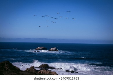 a flock of pelicans flying over a rough sea. - Powered by Shutterstock