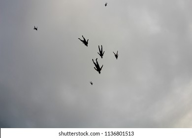 A flock of skydivers is in the cloudy sky.