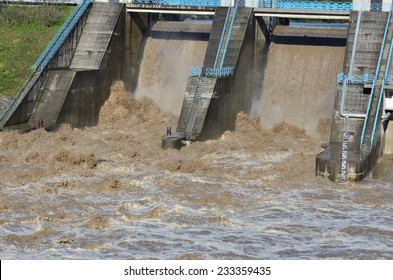 Flood water streaming over the top of a dam caused by excessive rainfall, possibly as a result of climate change