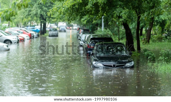 Flooded cars on the street of the city. Street\
after heavy rain. Water could enter the engine, transmission parts\
or other places. Disaster Motor Vehicle Insurance Claim Themed.\
Severe weather concept
