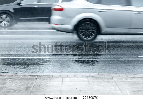 flooded city asphalt road with cars moving in high\
speed during heavy rain