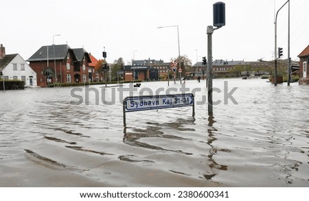 Flooded Danish city streets and traffic lights under storm surge and a sign with directions to the southern harbour dock