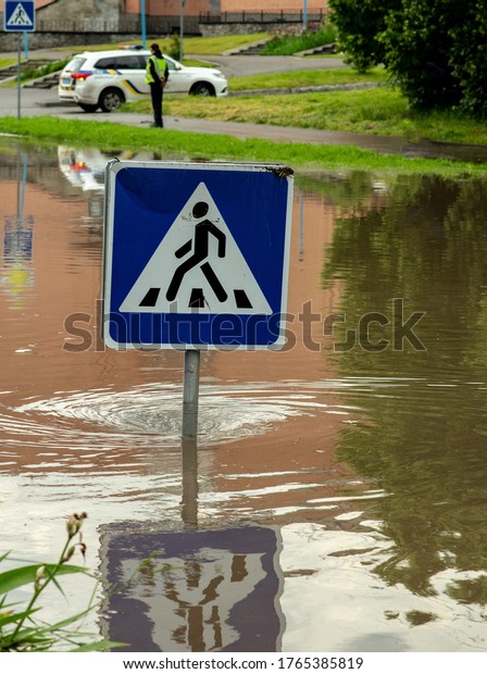Flooded intersection after a long rain. The\
warning sign \