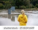 Flooded river. Worried woman looking at overflowing water during flood. Extreme weather and natural disaster