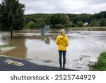 Flooded river. Worried woman looking at overflowing water during flood. Extreme weather and natural disaster