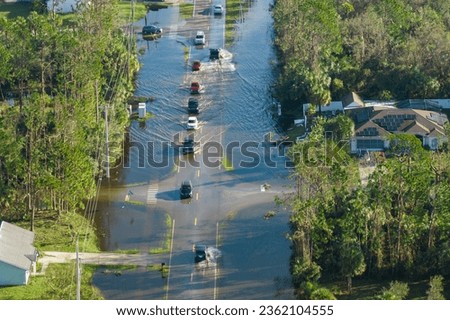 Flooded road in Florida after heavy hurricane rainfall. Aerial view of evacuating cars and surrounded with water houses in suburban residential area