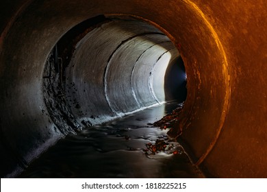 Flooded round sewer tunnel with water reflection