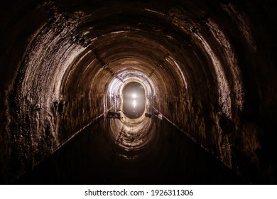 Flooded round sewer tunnel with water reflection.
