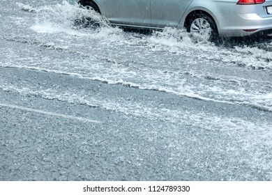 Flooded Street Roads. Car Driving Through Water Puddle And Spraying Water From The Wheels