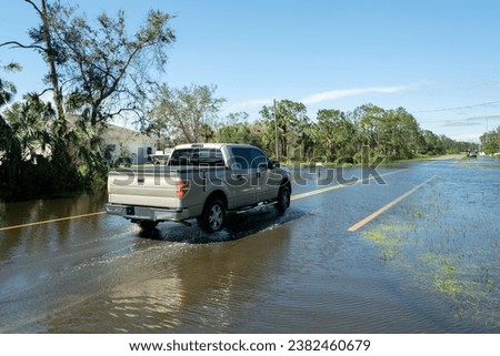 Flooded town street with moving cars submerged under water in Florida residential area after hurricane Ian landfall. Consequences of natural disaster