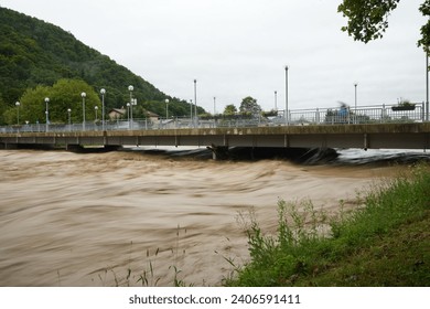Floods in Slovenia. There is debris in the water and people watching. 