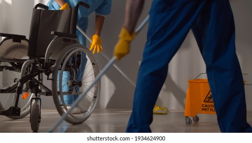 Floor Care And Cleaning Services With Washing Mop In Sterile Hospital. Cropped Shot Of Janitors Washing Floor In Clinic Corridor. Healthcare And Hygiene Concept