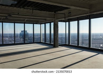 Floor to ceiling windows with angular shadows in an empty office space awaiting development in a large highrise on clear day