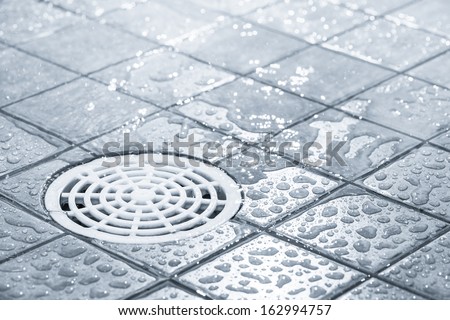 Floor drain, running water in shower, tinted black and white image