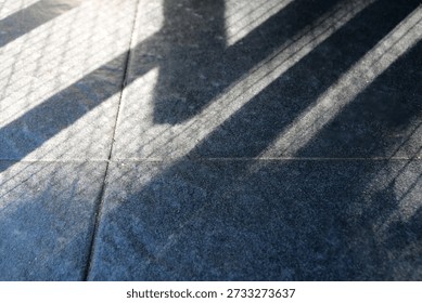 Floor features bold diagonal shadows from a railing, creating a moody geometric composition. The interplay of light and texture evokes urban architecture and a calm, cool ambiance.