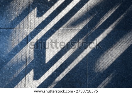 Floor features bold diagonal shadows from a railing, creating a moody geometric composition. The interplay of light and texture evokes urban architecture and a calm, cool ambiance.