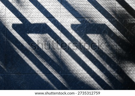 Floor features bold diagonal shadows from a railing, creating a moody geometric composition. The interplay of light and texture evokes urban architecture and a calm, cool ambiance.