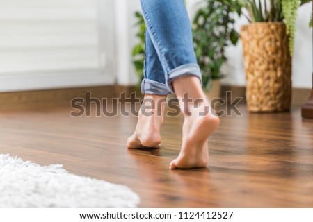 Floor heating. Young woman walking in the house on the warm floor. Gently walked the wooden panels.
