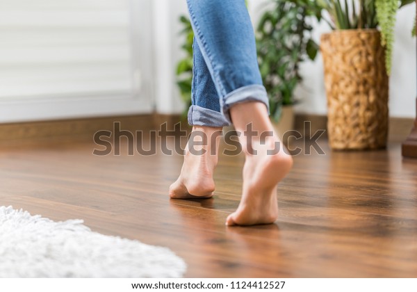 Floor heating. Young woman\
walking in the house on the warm floor. Gently walked the wooden\
panels.