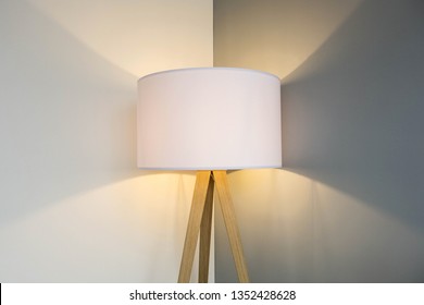 floor lamp standing near white gray wall with big lamp shade modern design, symmetrical light background texture close-up