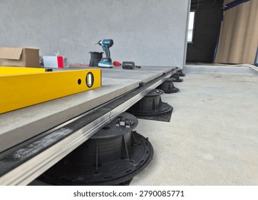 Floor level view of an access raised floor installation with adjustable pedestals and hand tools.