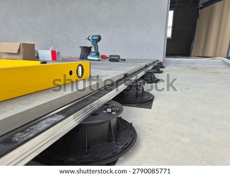 Floor level view of an access raised floor installation with adjustable pedestals and hand tools.