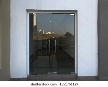 Floor Mounted Frame Less  Double Leaf Glass Doors Hinged On The Floor In Door Opening In Between The White Color Texture Painted For Exteriors Walls And Fixed In The Entrance 