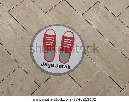 a floor with a red shoe in a circle and an inscription meaning "keep your distance"