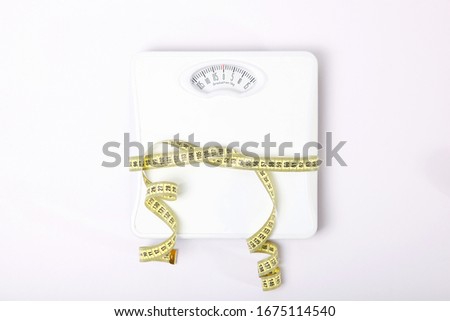 floor scales and tape measure on a colored background top view. Healthy lifestyle concept, healthy eating. Body weight control.
