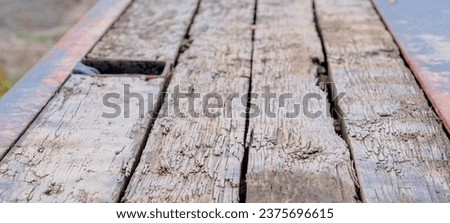 The floor of the semi-trailer for transporting heavy equipment is made of quite damaged thick boards.Thick boards (floor of a large trailer) worn by heavy construction equipment (excavators, etc.).