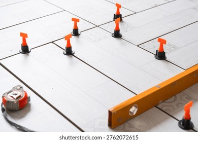 Floor tiling in progress, ceramic tiles with spacers and leveling system, repair and renovation work, home improvement, professional installation tools.