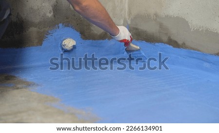 Floor waterproofing in blue. A worker is applying waterproofing paint to the floor in the bathroom.