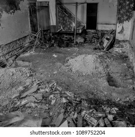 Flooring Removed for Underpinning Works, Showing Stripping of Materials, Piles of Rubble, and an Old Fashioned Stairway and Wallpaper on a Black and White Background - Shutterstock ID 1089752204