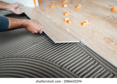 Flooring and tiling. Professional tiler placing floor tiles on adhesive surface. - Shutterstock ID 2086633294