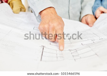 Floorplan and architect pointing and making decisions about building construction