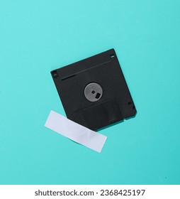 Floppy disk is taped to a blue wall. Conceptual photo, minimalism.