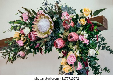 Floral Arrangement Of Colorful, Fresh Native Australian Wildflowers And Roses, Attached To The Corner Of A Timber Arch Arbor. Wedding Decoration. 