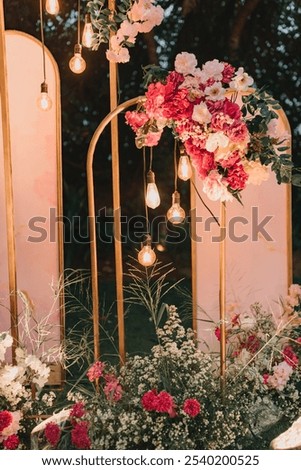 floral arrangement with hanging Edison bulbs and lush greenery, set against a pink background for a romantic ambiance