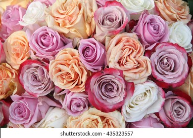 A Floral Arrangement Made Off Big Orange, White And Purple Lila Roses