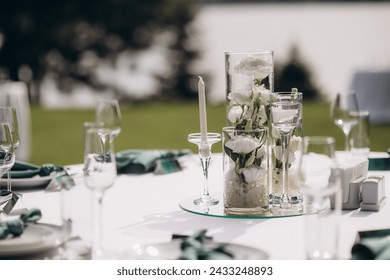 Floral arrangements of white flowers in transparent glass vases. On the festive table in the wedding banquet area, compositions of flowers and greenery, candles are placed. - Powered by Shutterstock