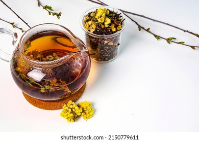 Floral black tea brewed in a transparent teapot. Hot drink on the table and granulated tea in a jar. Tea presentation concept. Method of brewing and storage. Still life