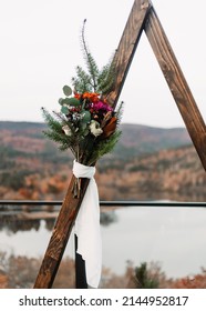 Floral Bouquet Attached To A Triangle Wedding Arbor On A Scenic Background By The River And Mountains.